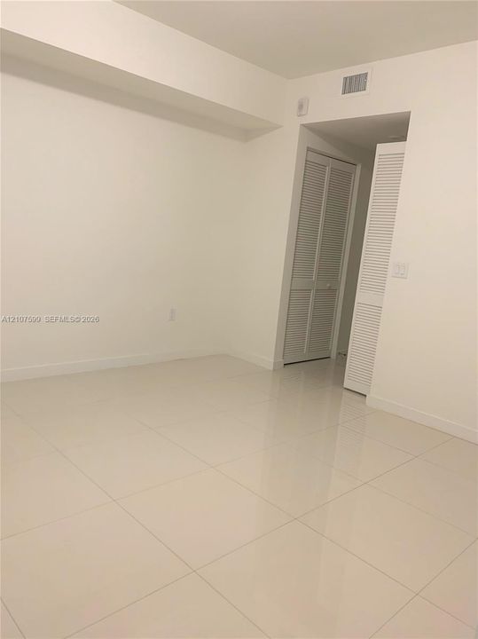 Interior space featuring large-format tile flooring, neutral walls, and dual louvered-style closet doors