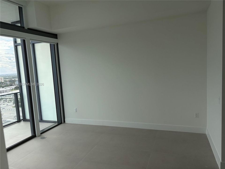 Floor-to-ceiling glass panel windows, large-format tile flooring, and exterior balcony access