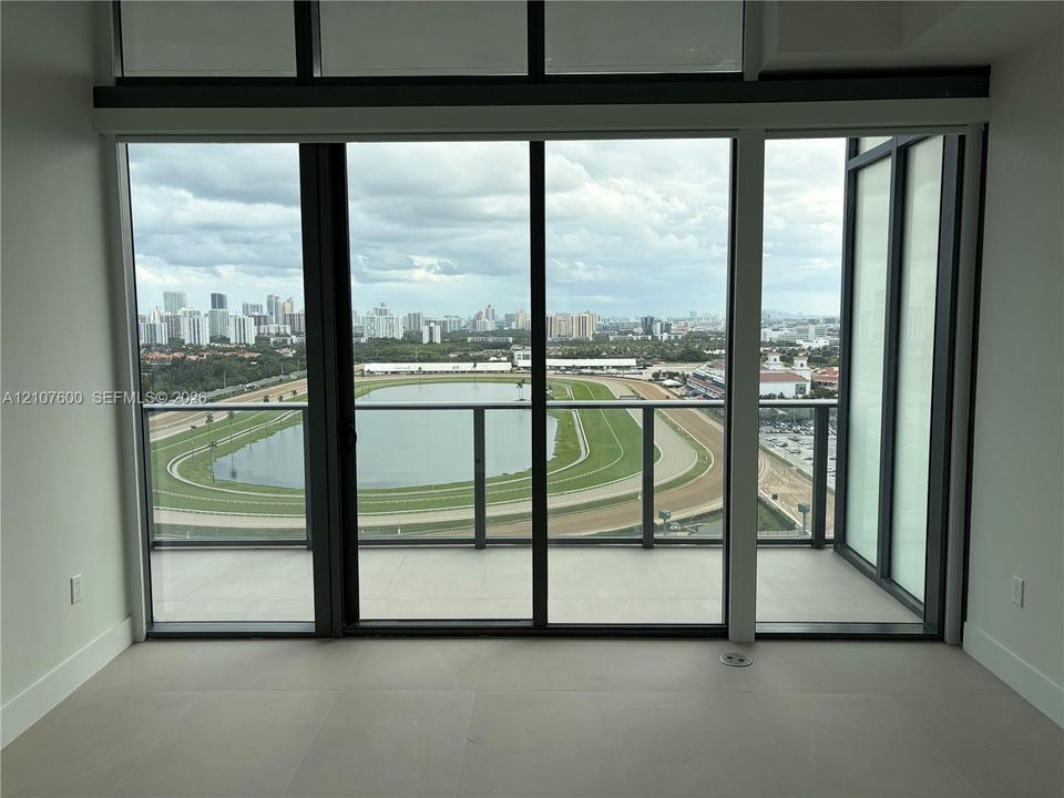loor-to-ceiling glass windows, ceramic tile flooring, and a glass-paneled balcony overlooking the racetrack and city skyline
