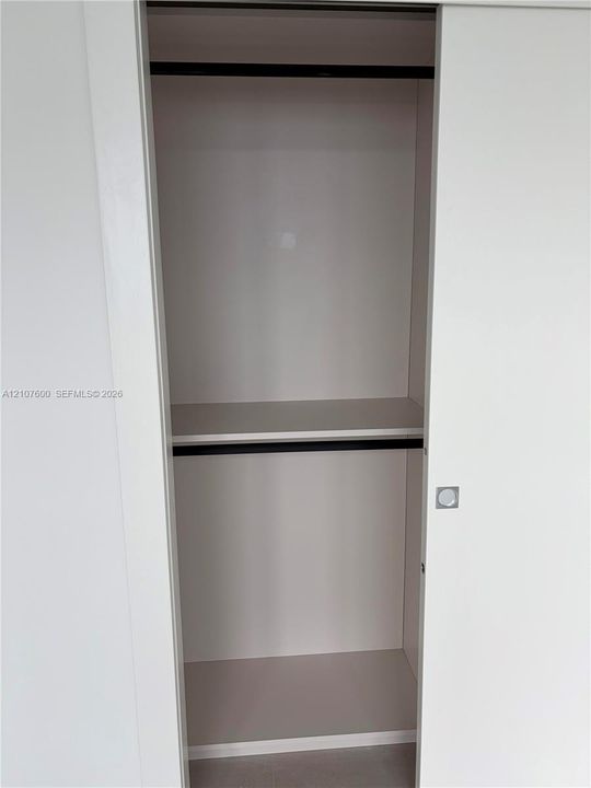 Sliding closet doors featuring a white finish, horizontal shelving, built-in rods, and a square metal handle