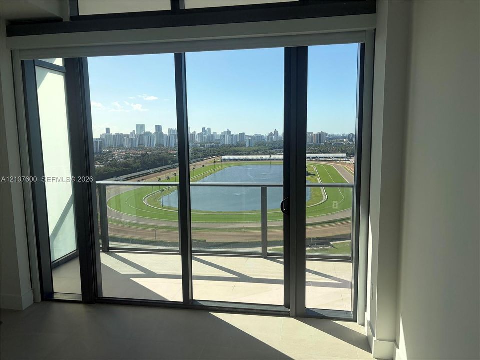 Floor-to-ceiling sliding glass doors, private balcony, metal railing, and expansive cityscape scenery