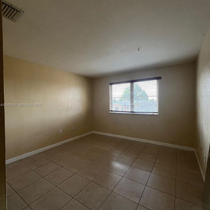 Neutral-toned room featuring light-colored tile flooring and a horizontal window with adjustable blinds