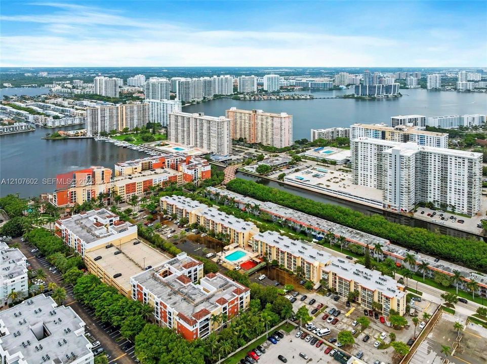 Aerial perspective of waterfront urban landscape featuring canals, residential mid-rise structures, landscaped grounds, and parking facilities