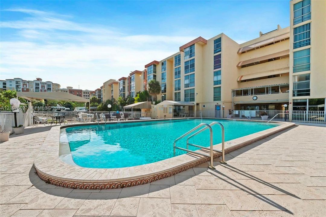 Swimming pool featuring stone-paver decking, metal entry handrails, and a dedicated sunshade structure