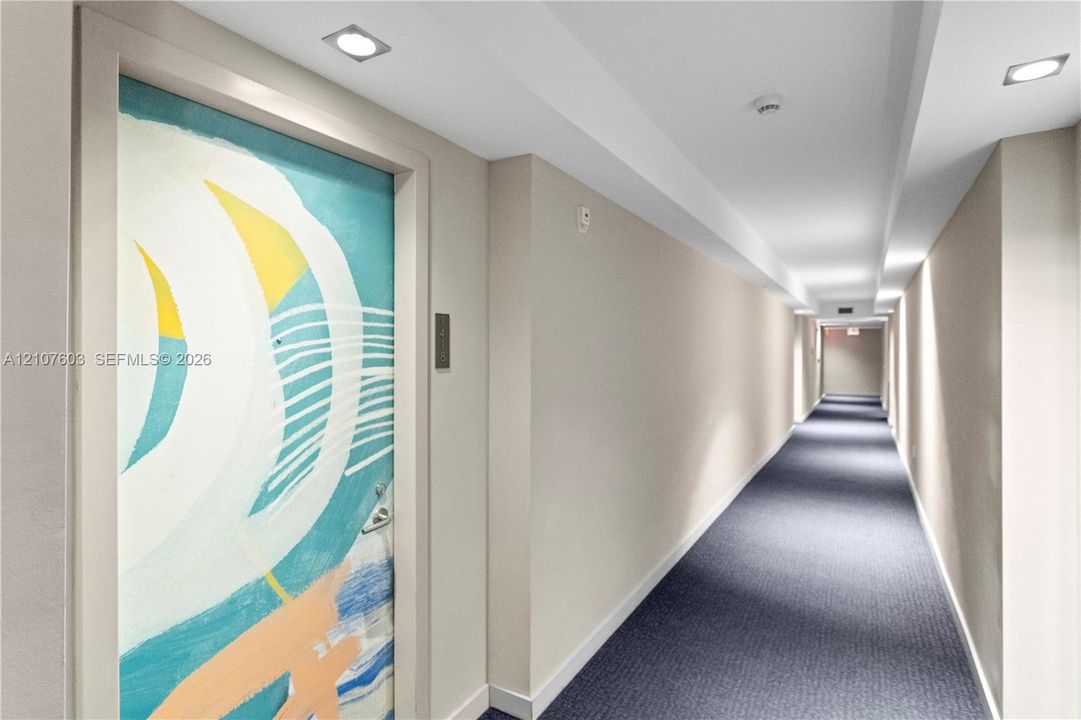 Hallway featuring recessed lighting, painted walls, carpeted flooring, and a patterned interior door