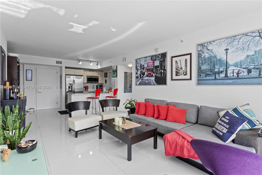 Open-concept interior featuring high-gloss tile flooring, smooth ceilings, and a kitchen equipped with stone-surfaced countertops and stainless-steel appliances