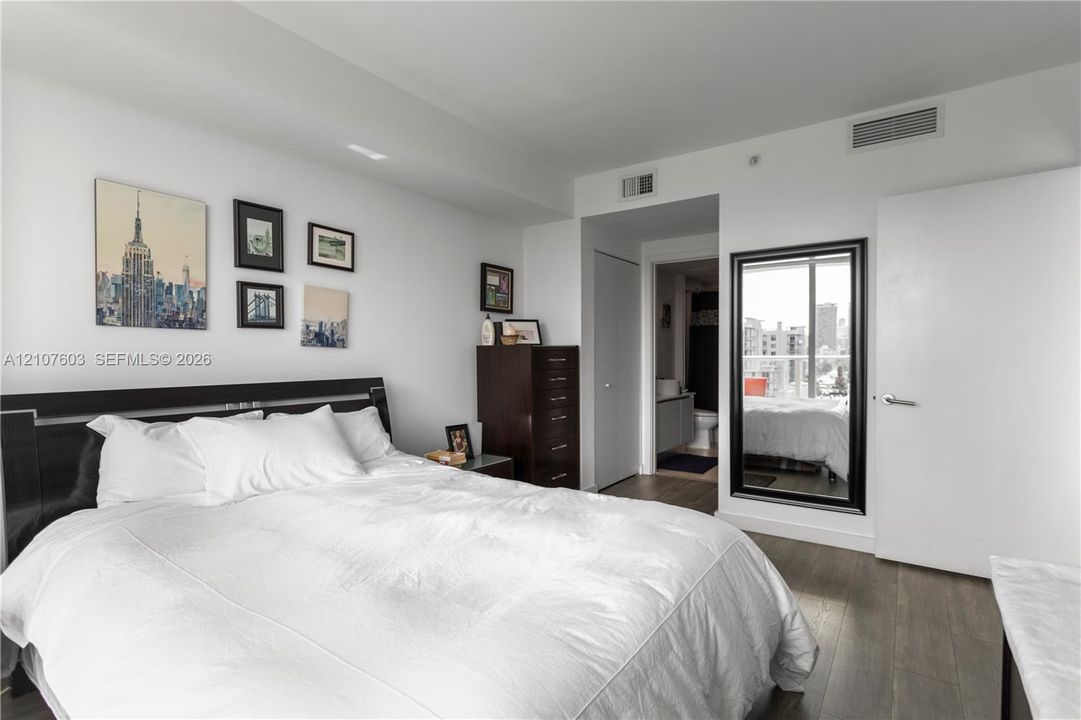 Wood-finish flooring, full-length wall mirror with a black frame, and ceiling-integrated climate control system