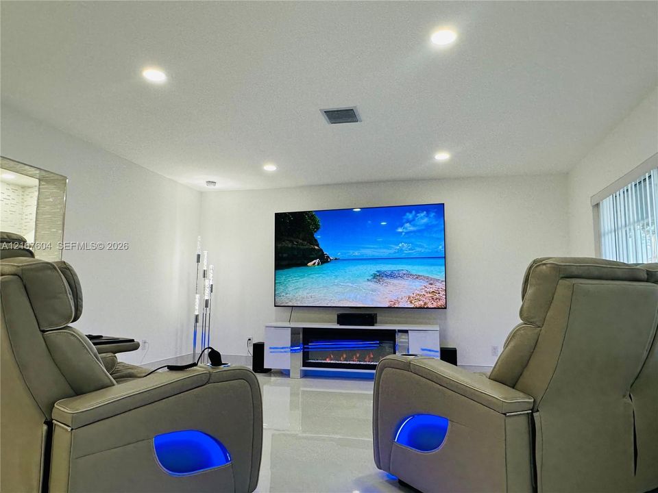 Recessed ceiling lighting, polished flooring, and a built-in electric fireplace unit with a high-gloss finish