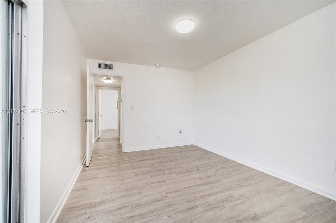 Room featuring light-toned wood-finish flooring, neutral walls, and a circular flush-mount ceiling light fixture