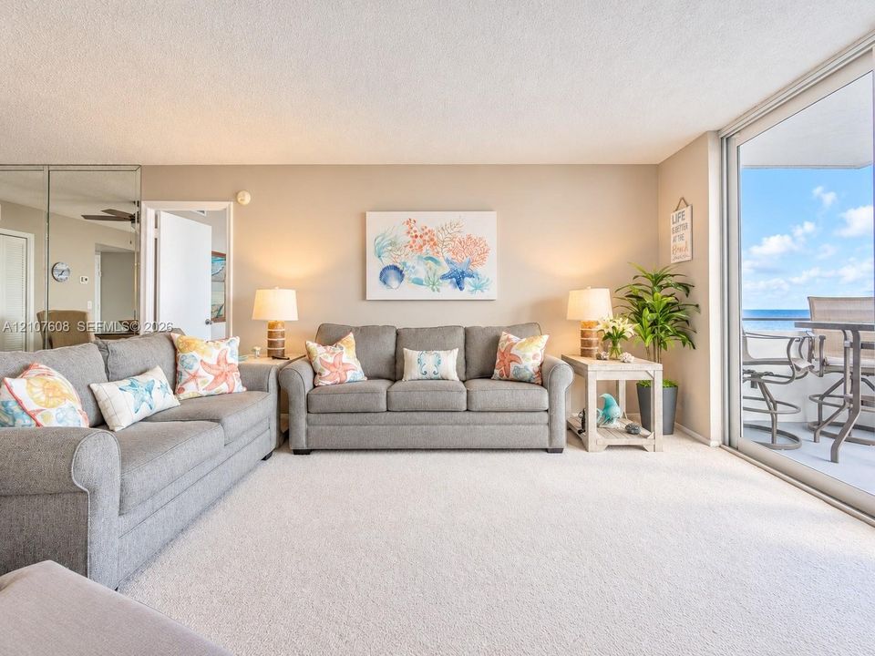 Full-height mirrored wall paneling, wall-to-wall carpeting, and sliding glass doors with access to an exterior balcony