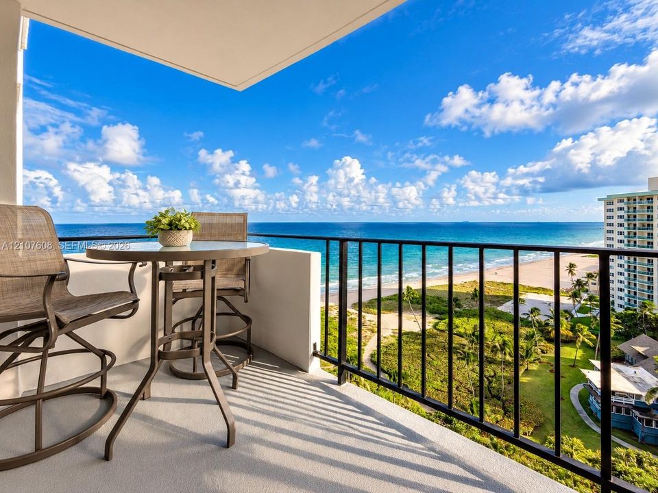 Covered balcony featuring concrete flooring and a metal railing overlooking the coastline and ocean