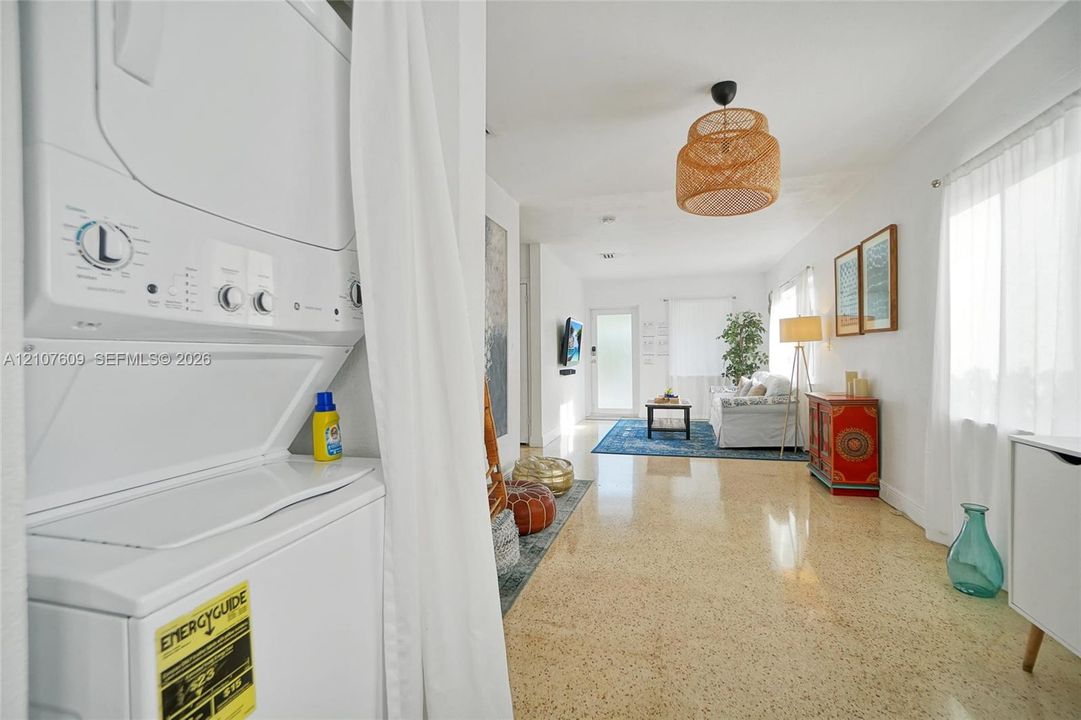Stacked laundry unit, polished terrazzo flooring, woven pendant lighting, and natural light via multiple windows