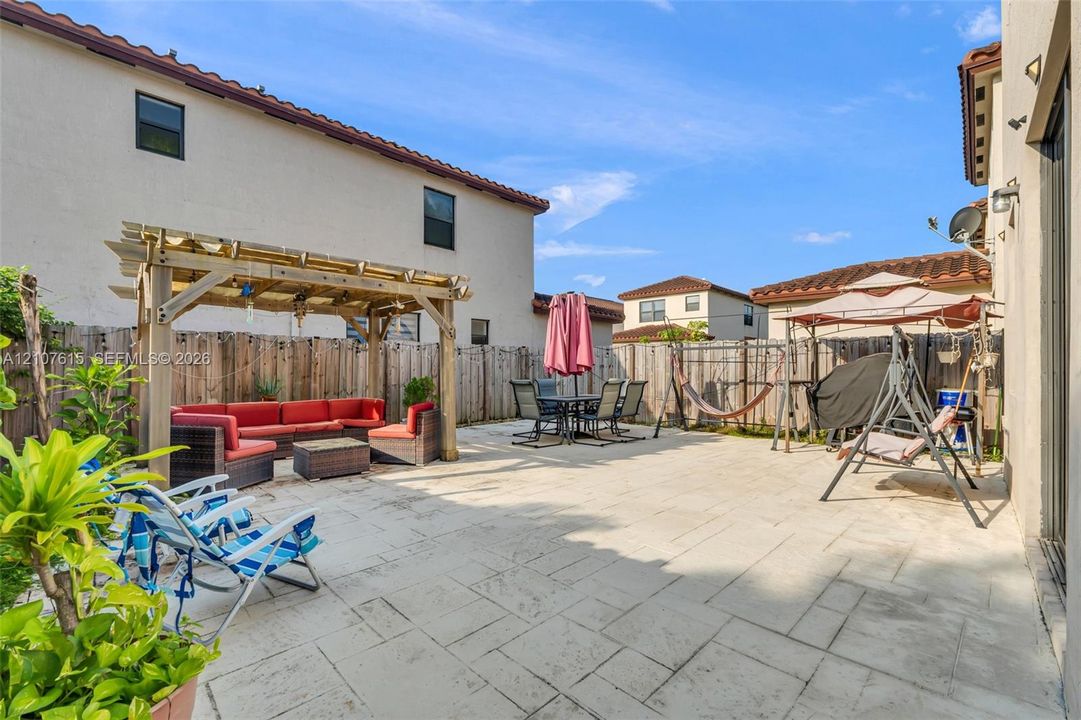 Rear patio featuring concrete tile pavers, a wood-frame pergola, and a wood privacy fence