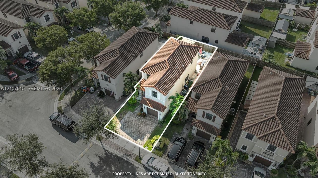 Two-story residence featuring a clay tile roof, paved driveway, attached garage, and fenced backyard