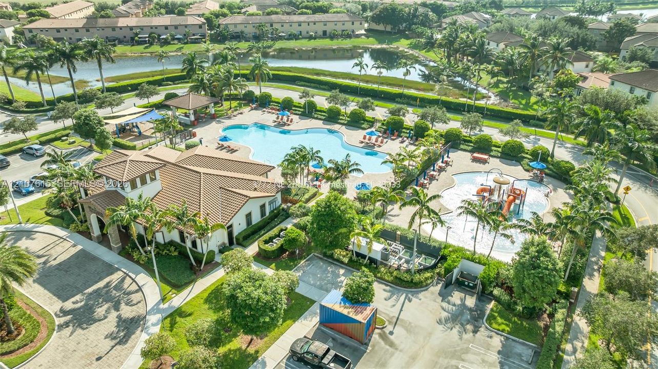 Community amenity complex featuring a pool, a water play area with slides, a pavilion, and landscaped grounds