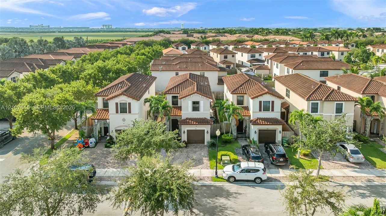Aerial perspective of two-story residences featuring tile roof systems, stucco exteriors, paver driveways, and integrated garage doors