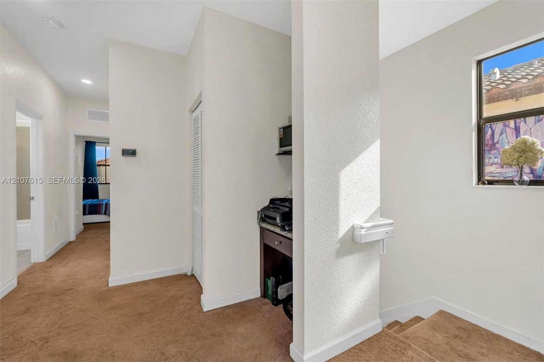 Built-in desk area with stone-surface countertop, carpeted flooring, neutral wall finishes, and louvered-door closet