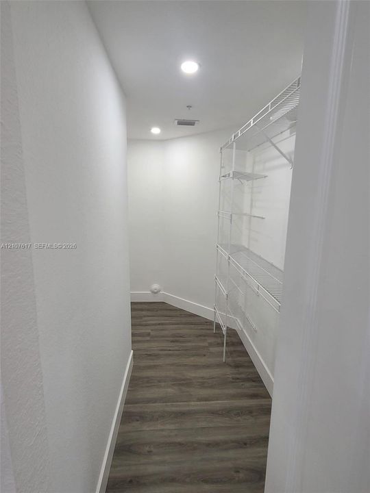 Walk-in storage space featuring wood-finish flooring and integrated white wire shelving