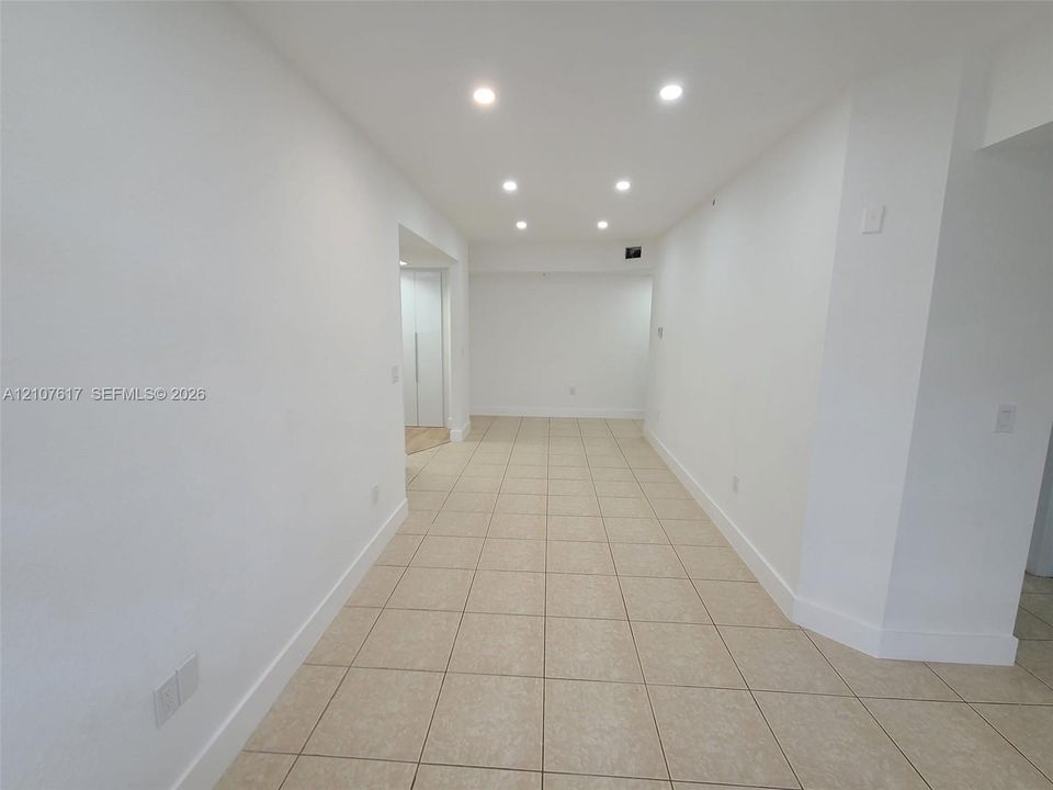 Interior space featuring neutral tile flooring, recessed ceiling lighting, and crisp white wall finishes
