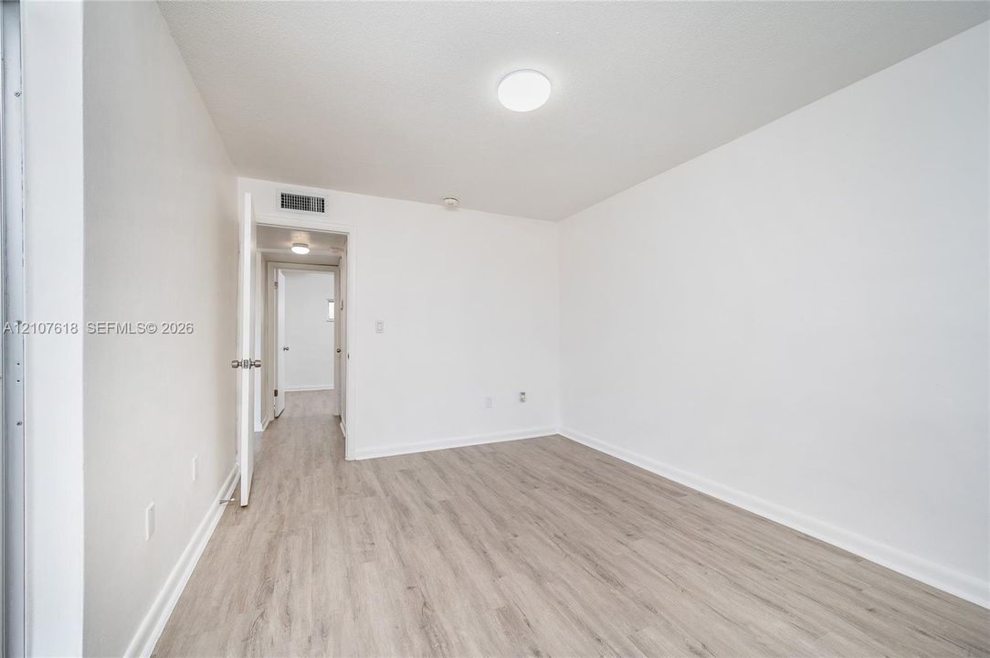 Interior room featuring wood-finish flooring, white walls, and a flush-mount ceiling light fixture