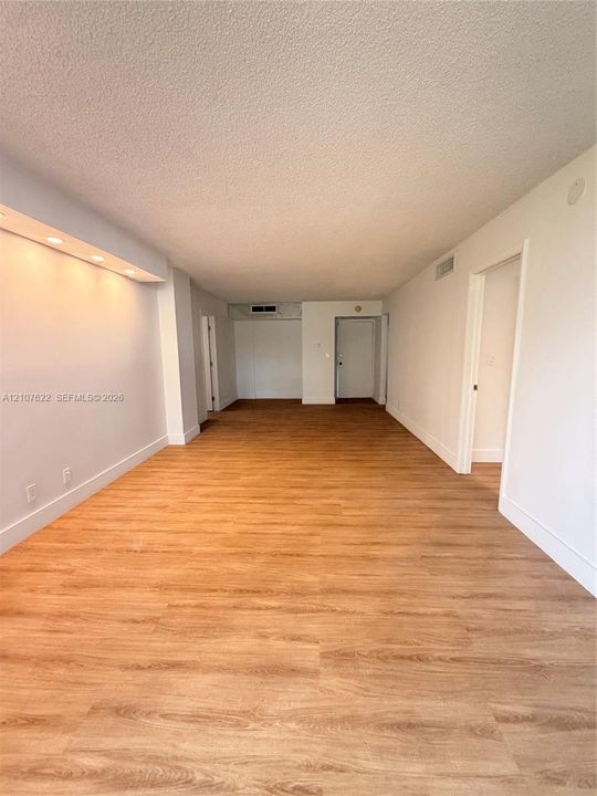 Open-concept interior featuring wood-finish flooring, recessed architectural soffit lighting, and neutral wall tones