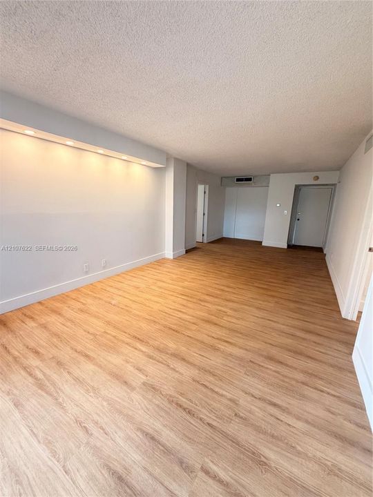 Open floor plan featuring wood-finish flooring, recessed soffit lighting, and neutral wall tones