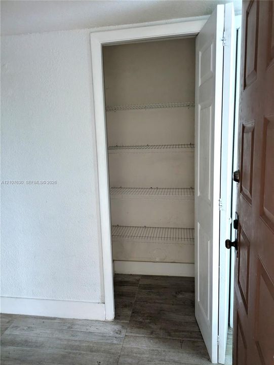 Storage closet featuring white wire shelving and wood-finish flooring