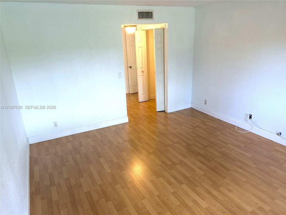 Wood-finish flooring and white interior wall surfaces featuring a set of bifold closet doors