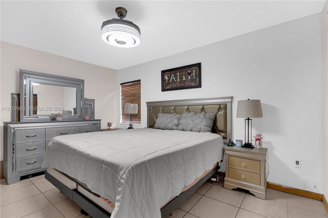 Neutral-toned wall finish, ceramic tile flooring, and integrated ceiling fan with circular light fixture