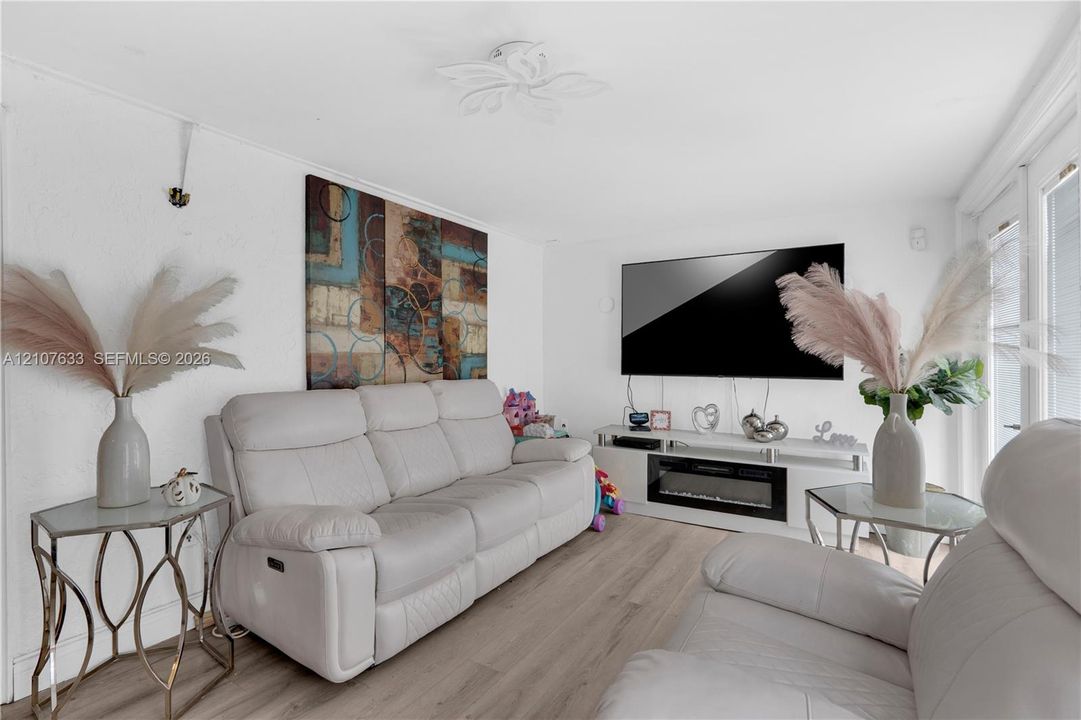 Wood-finish flooring, white walls, flush-mount floral-style ceiling fixture, and glass-paneled patio doors