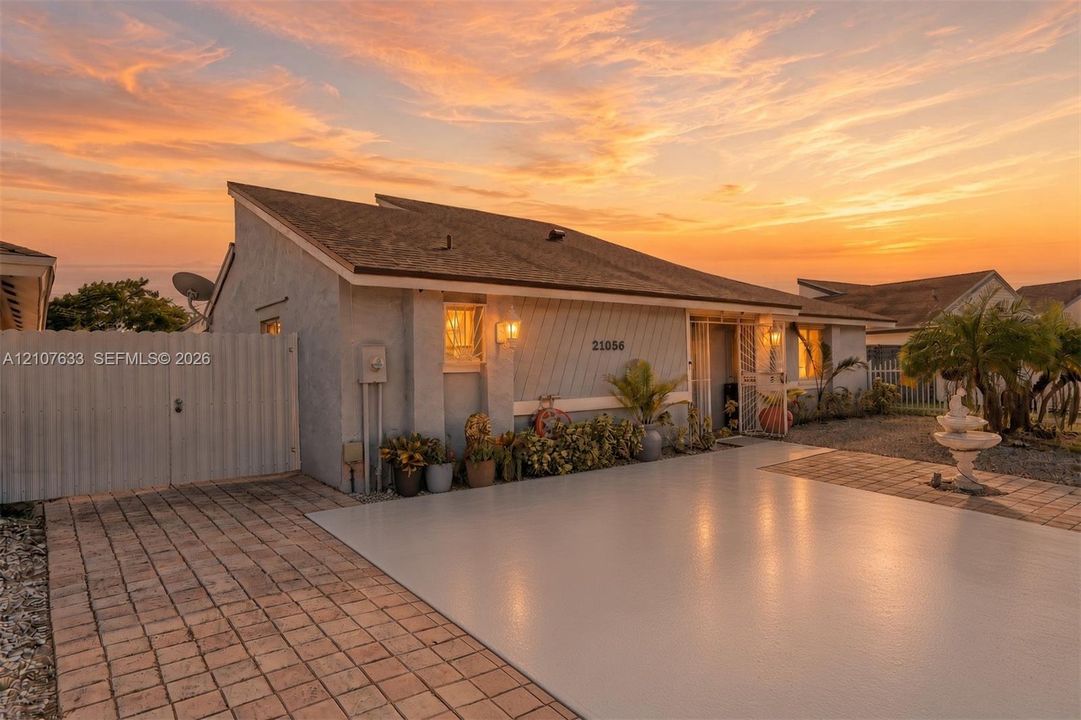 Single-story residence featuring a shed roofline, stucco exterior, paved driveway, and gated side access