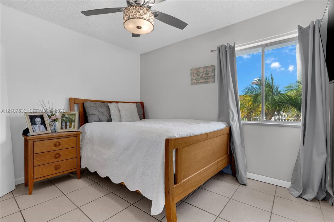 Room featuring large-format neutral floor tile, a central ceiling fan with an integrated light fixture, and a single-pane window