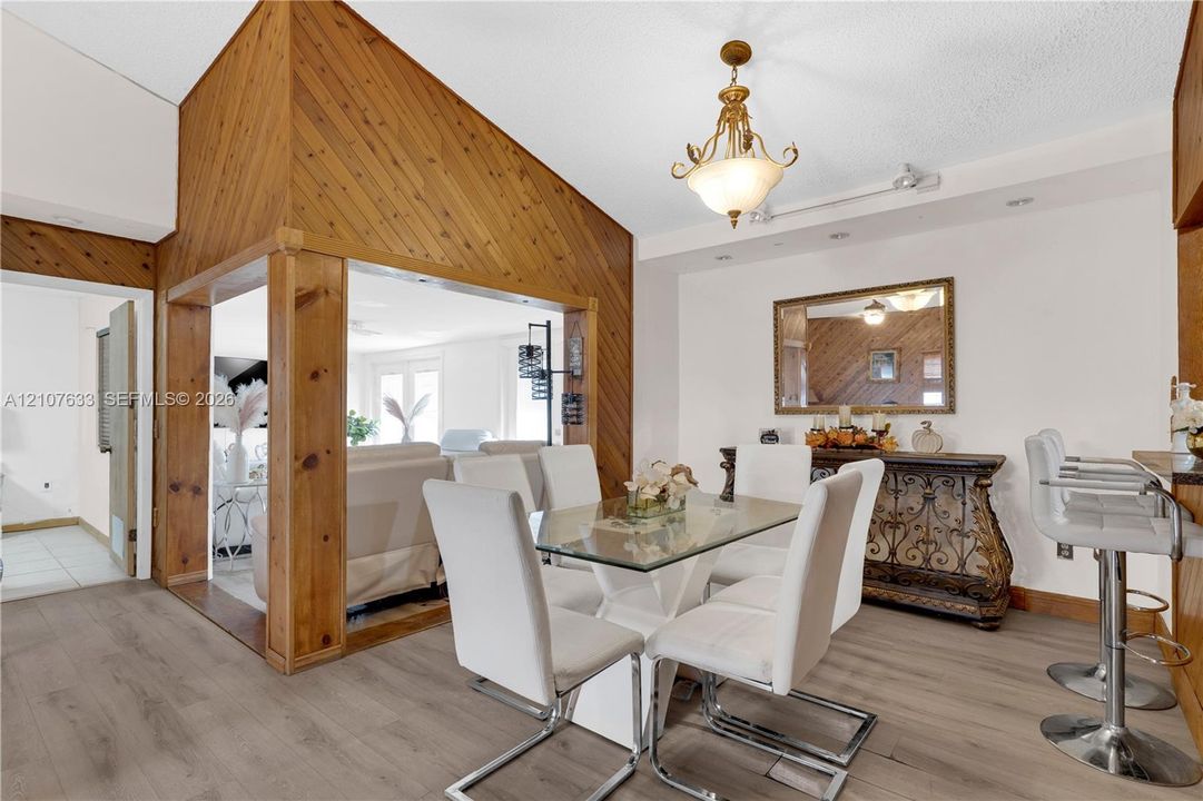 Dining area featuring diagonal wood-panel accent walls, wood-finish flooring, and a decorative multi-arm chandelier
