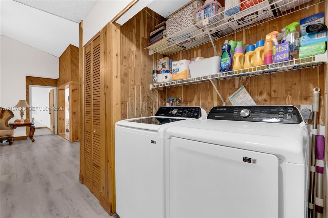 Laundry area featuring wood-paneled walls, louvered closet doors, and wire-rack shelving