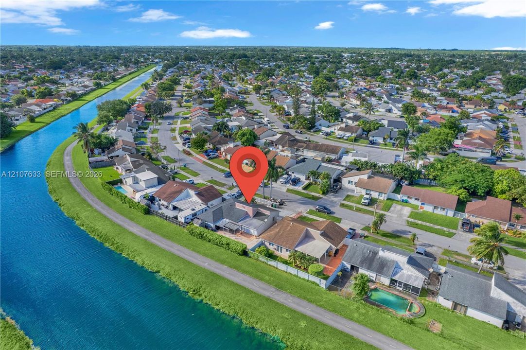 Aerial perspective of residential property featuring a direct water-facing location, canal frontage, and expansive neighborhood setting