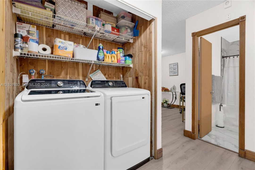 Laundry area featuring vertical wood-plank wall paneling and dual-tier wire shelving
