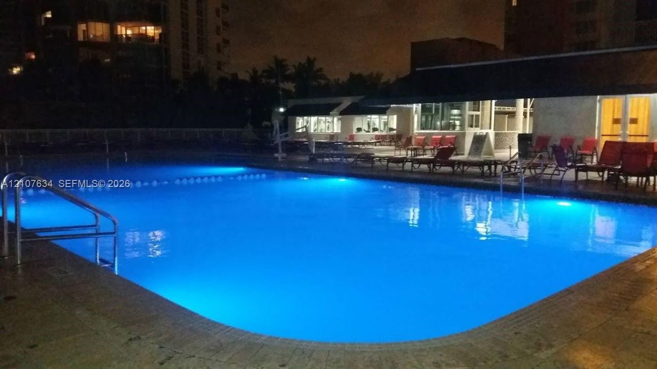 Rectangular swimming pool featuring a stone-tile deck and built-in metal handrails