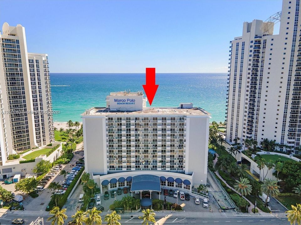 High-rise beachfront property featuring balconies, a covered entryway, and direct access to the coastline