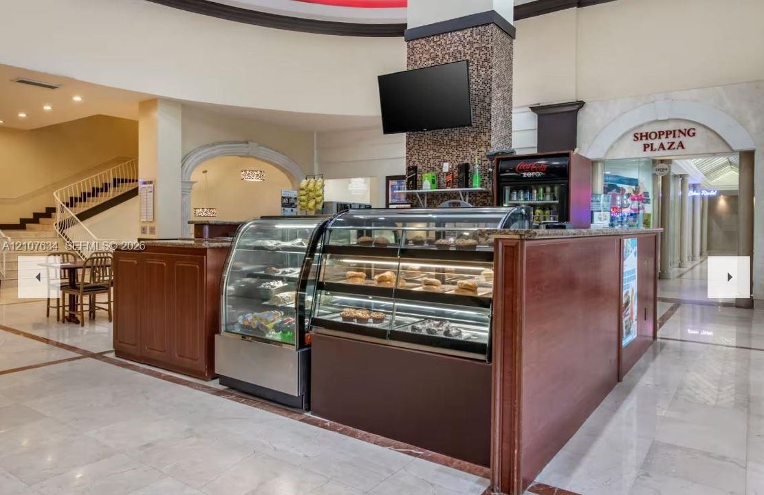 Commercial service counter featuring wood-finish cabinetry, stone-style countertop, glass display cases, and an arched entryway architectural detail