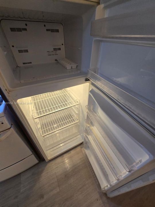 Top-mount refrigerator featuring wire shelving, door storage bins, and integrated interior lighting