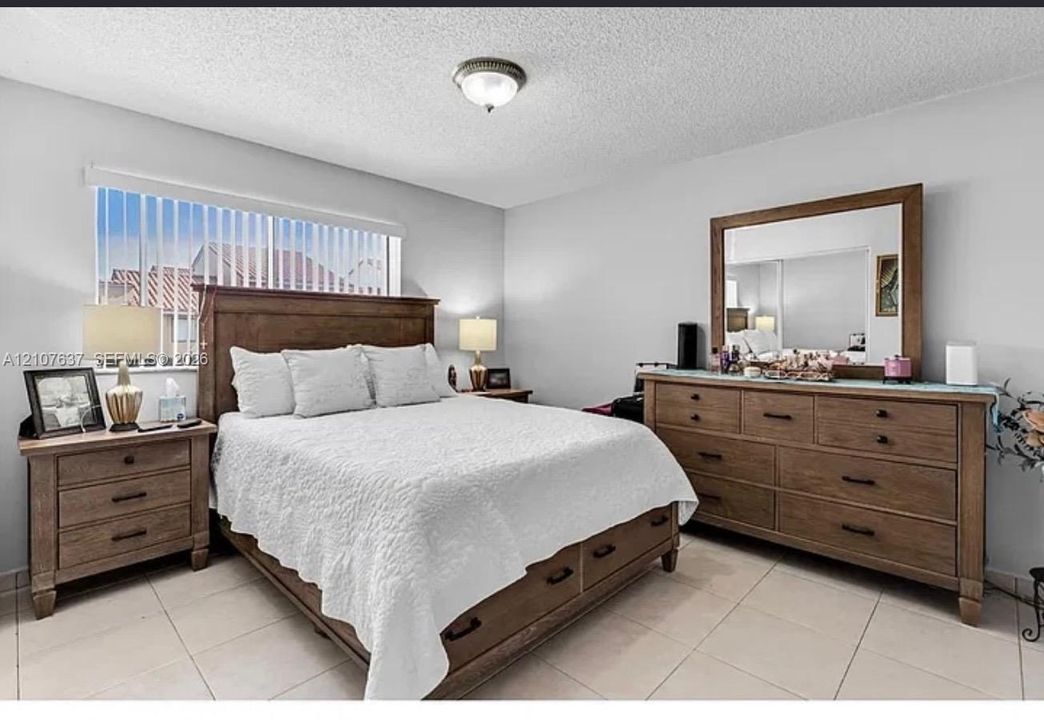 Neutral wall tones, large-format tile flooring, and vertical window blinds