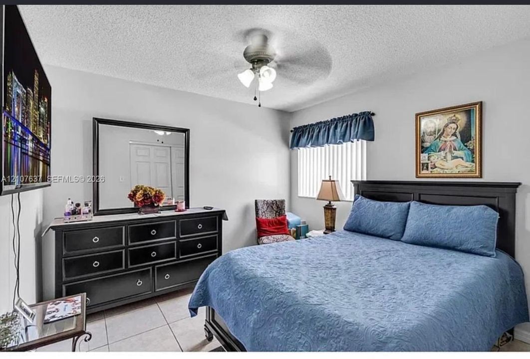 Room featuring tile flooring, ceiling fan with integrated lighting, and vertical window blinds