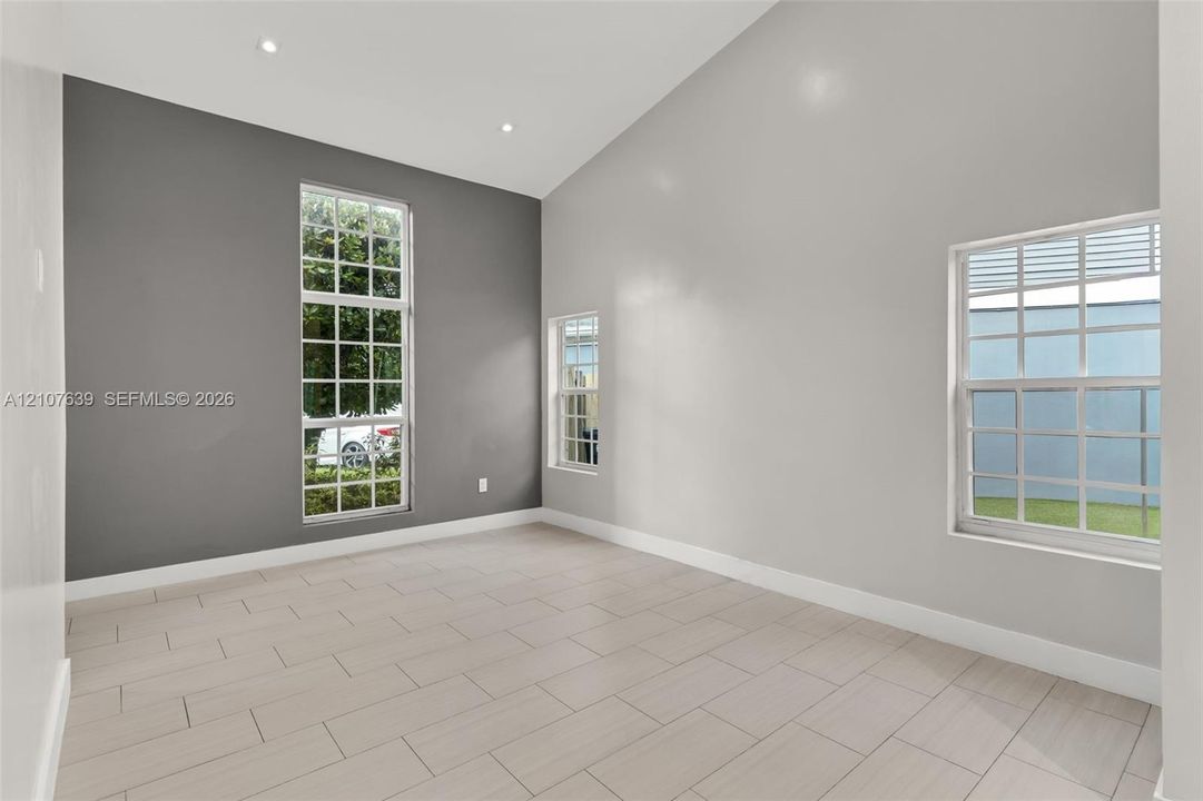 Vaulted ceilings featuring recessed lighting, large grid-pattern windows, and neutral-tone tile flooring