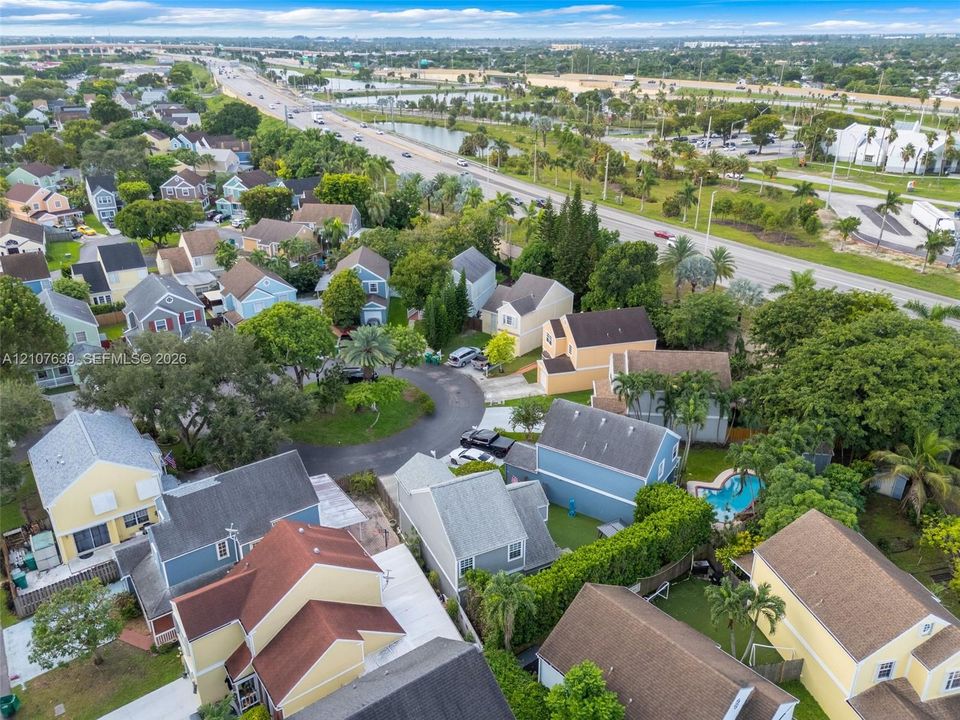 Aerial perspective of a residential community featuring multi-story dwellings, paved cul-de-sacs, and mature landscaping