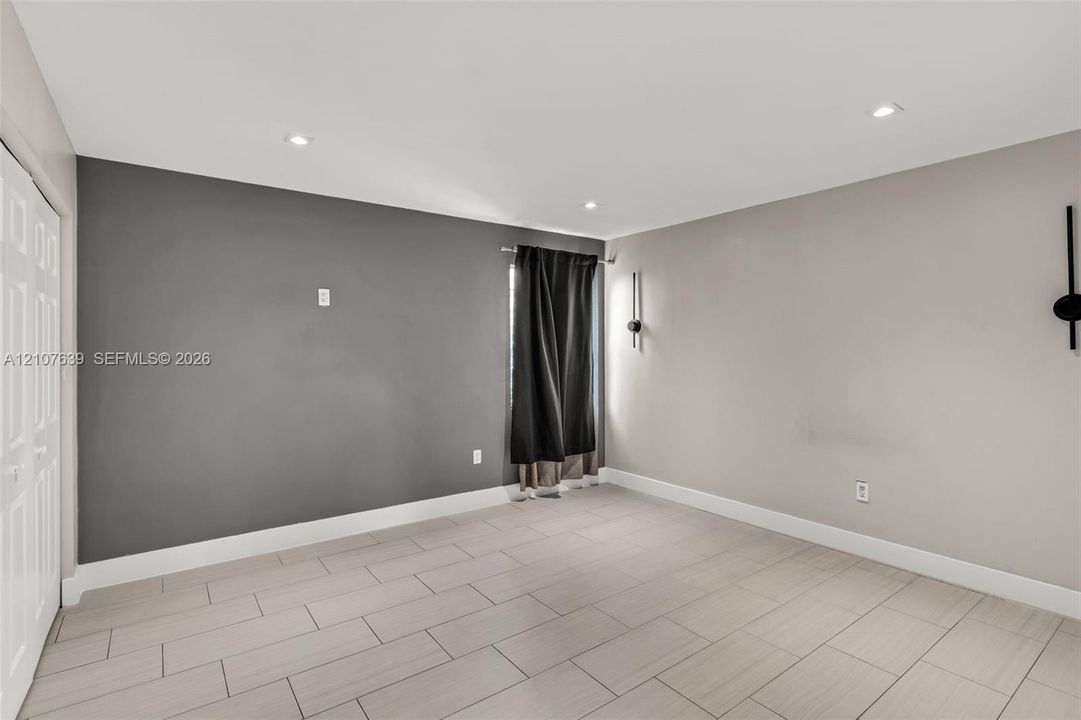 Interior space featuring neutral wall tones, large-format tile flooring, recessed ceiling lighting, and dual wall-mounted light fixtures