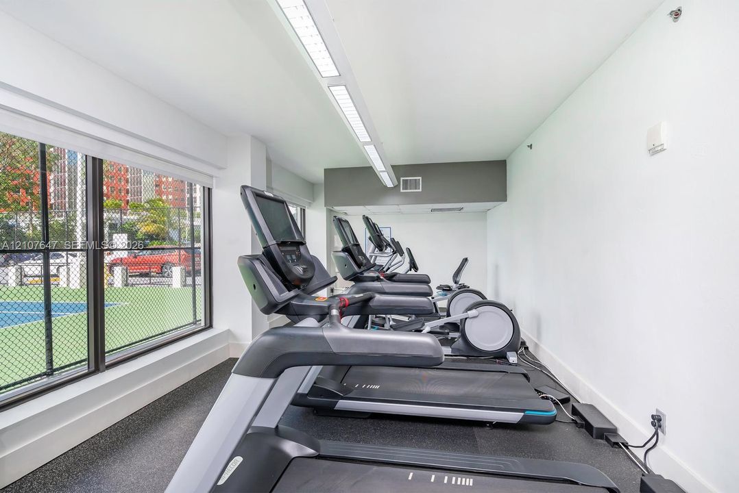 Fitness center featuring large floor-to-ceiling windows, recessed linear lighting, and durable rubber flooring