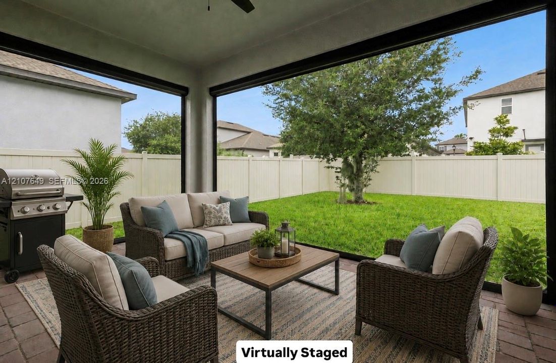 Screened-in patio featuring brick paver flooring, a ceiling fan, and a fenced-in backyard with a manicured lawn and mature tree