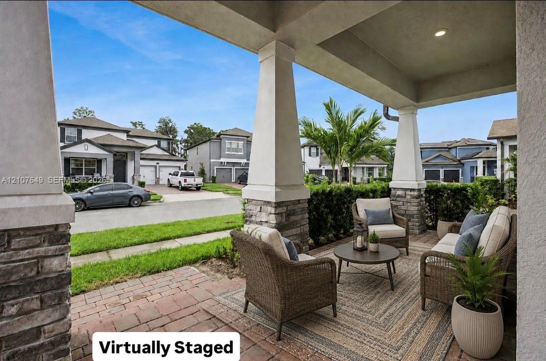 Covered front porch featuring tapered columns with stone-veneer bases and paver flooring
