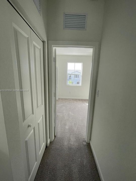 Hallway featuring bi-fold closet doors and neutral carpeting