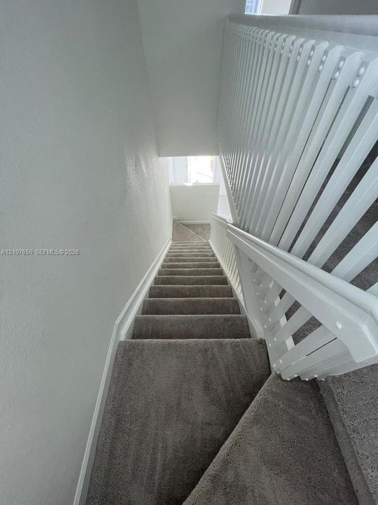 Staircase featuring wall-to-wall carpeting and a white vertical balustrade railing